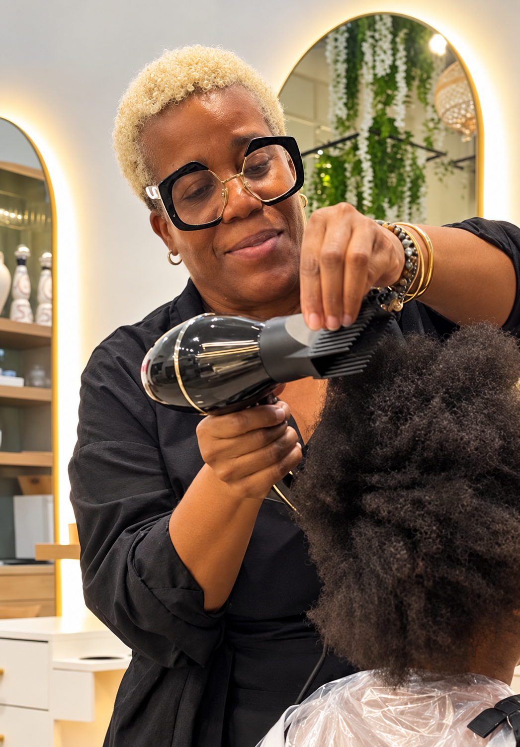 Mrs. Marva working on an adult client’s hair in the salon